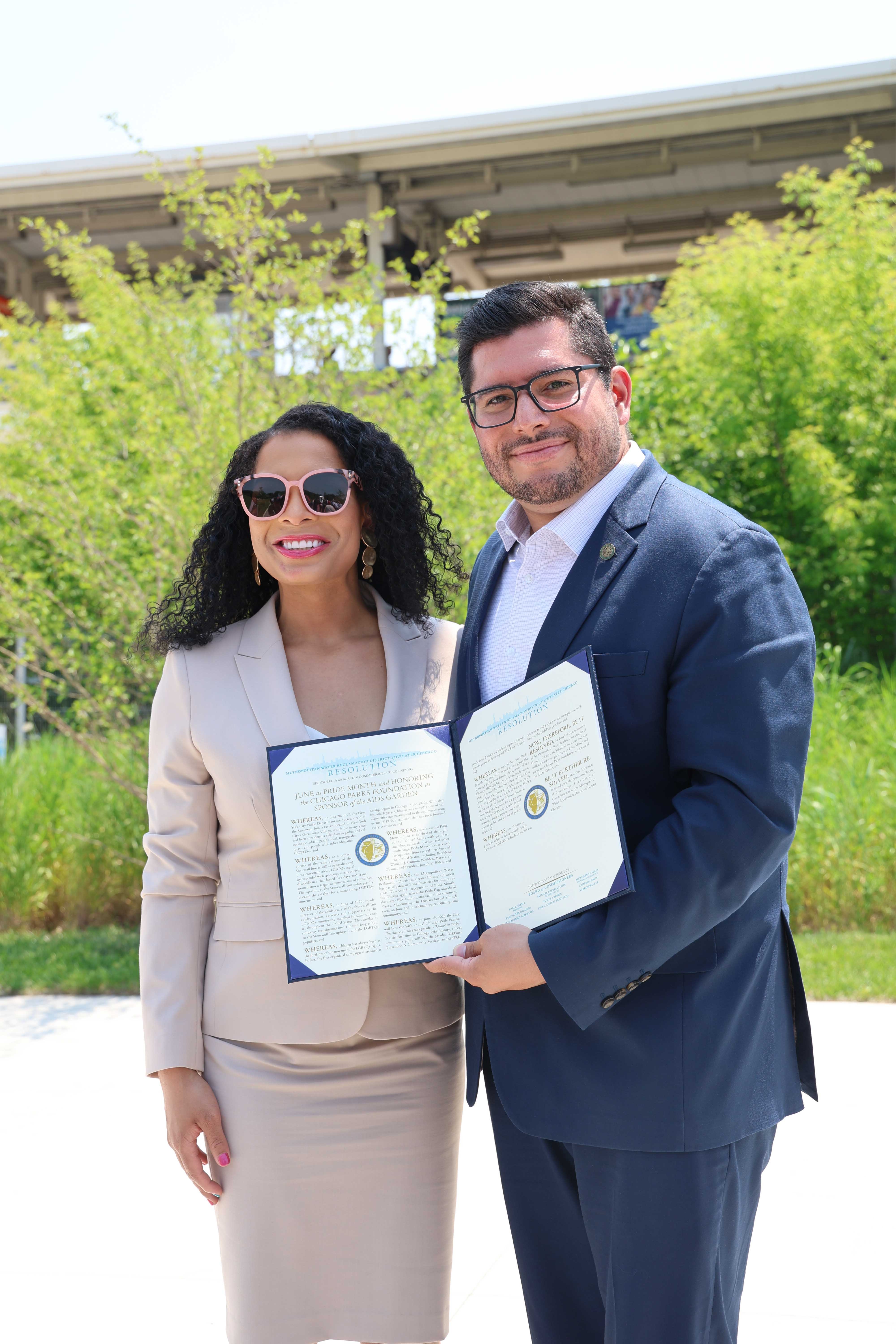 Two people in business attire hold a large, opened resolution document.